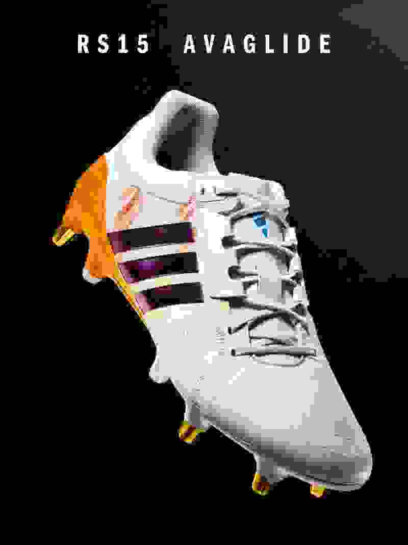 De afbeelding toont een witte en oranje voetbalschoen met de prominente tekst "RS15 AVAGLIDE" aan de zijkant.