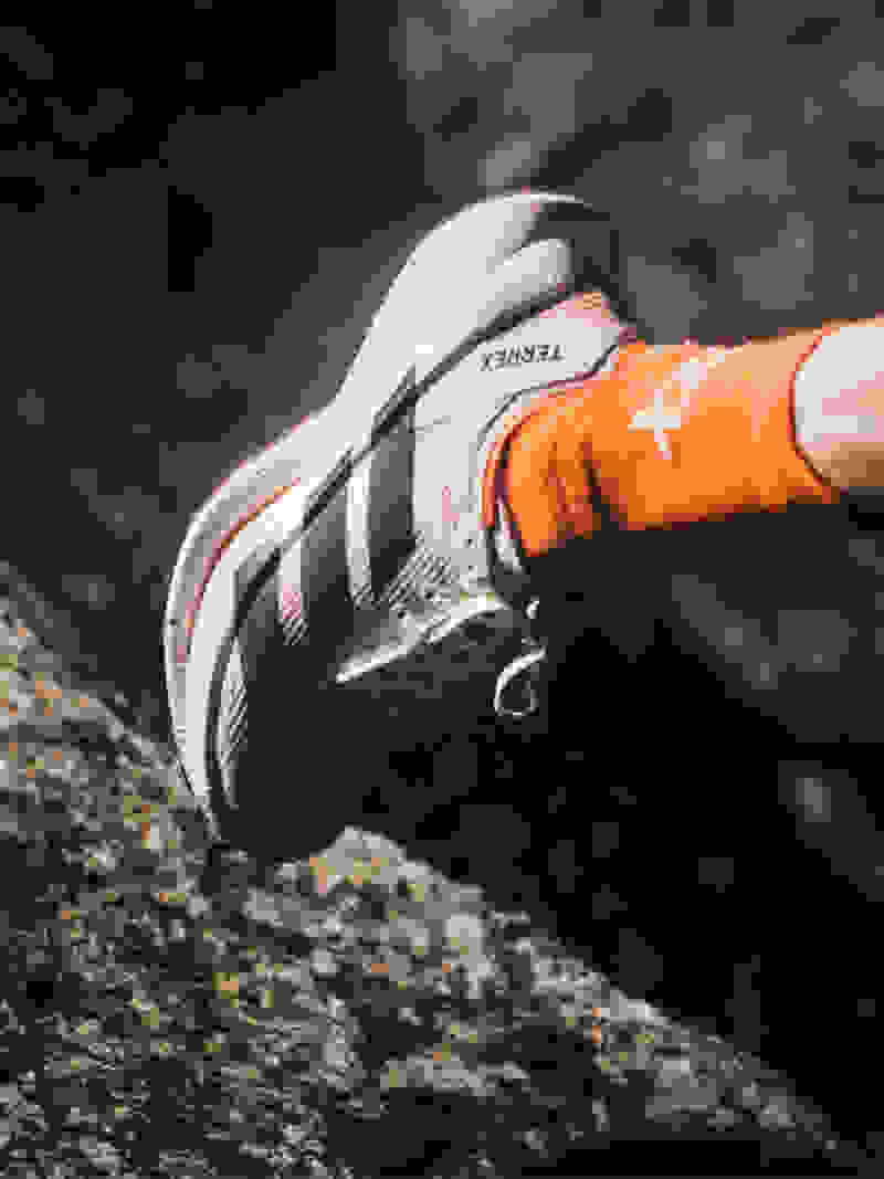 A close-up view of a person's foot wearing a white and orange athletic shoe on a rocky surface.