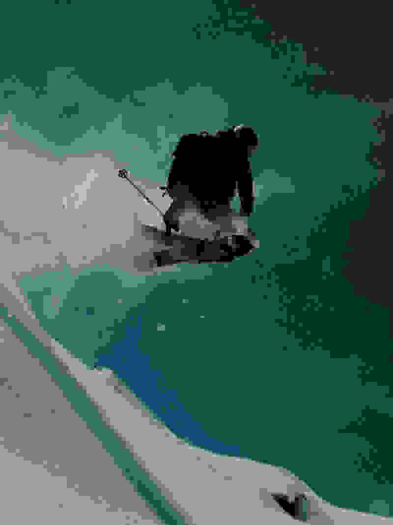 En person på et snowboard bliver fanget midt i et spring, omgivet af hvirvlende sne og en dramatisk, stormfuld himmel i baggrunden.