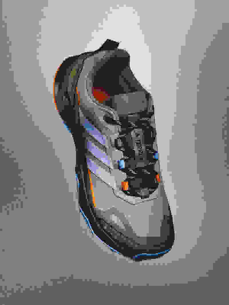 En grå og orange atletisk sko med snørebånd og en tekstureret sål, sat på en ensfarvet grå baggrund.