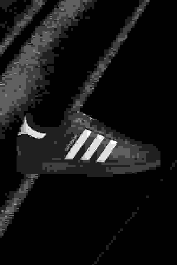Side view of black Superstar adidas sneaker.