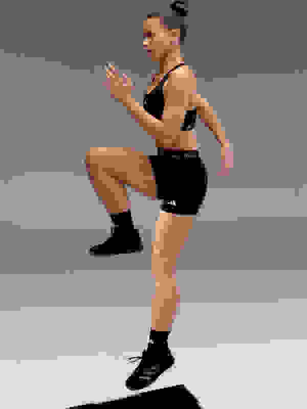 A person in athletic attire is performing a squat exercise on a plain gray background.