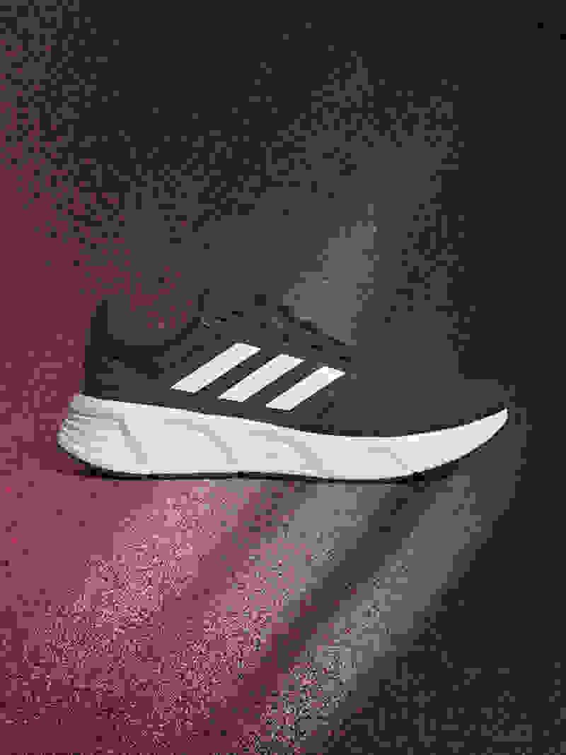 A navy blue and white athletic shoe is displayed against a dark, textured background with a reddish-brown hue.