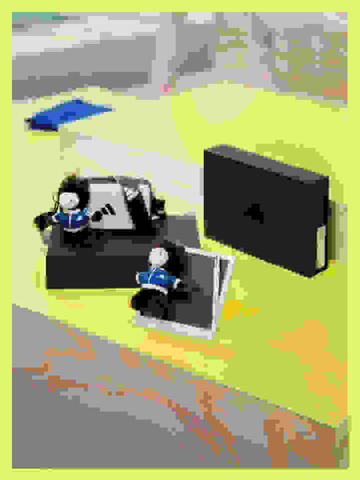 The image shows a collection of small plush figures, likely representing characters from a popular media franchise, arranged on a yellow surface with various black and blue geometric shapes in the background.