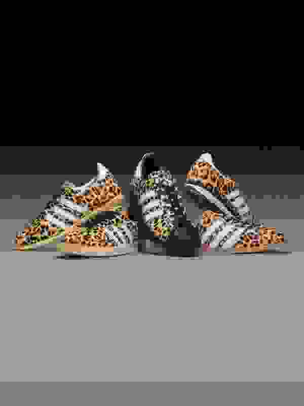 Three pairs of leopard-print sneakers with white stripes and soles against a dark background.