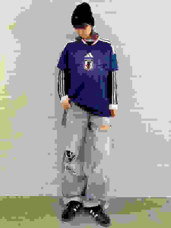 A person wearing a blue and white striped jersey, standing in front of a plain white wall.