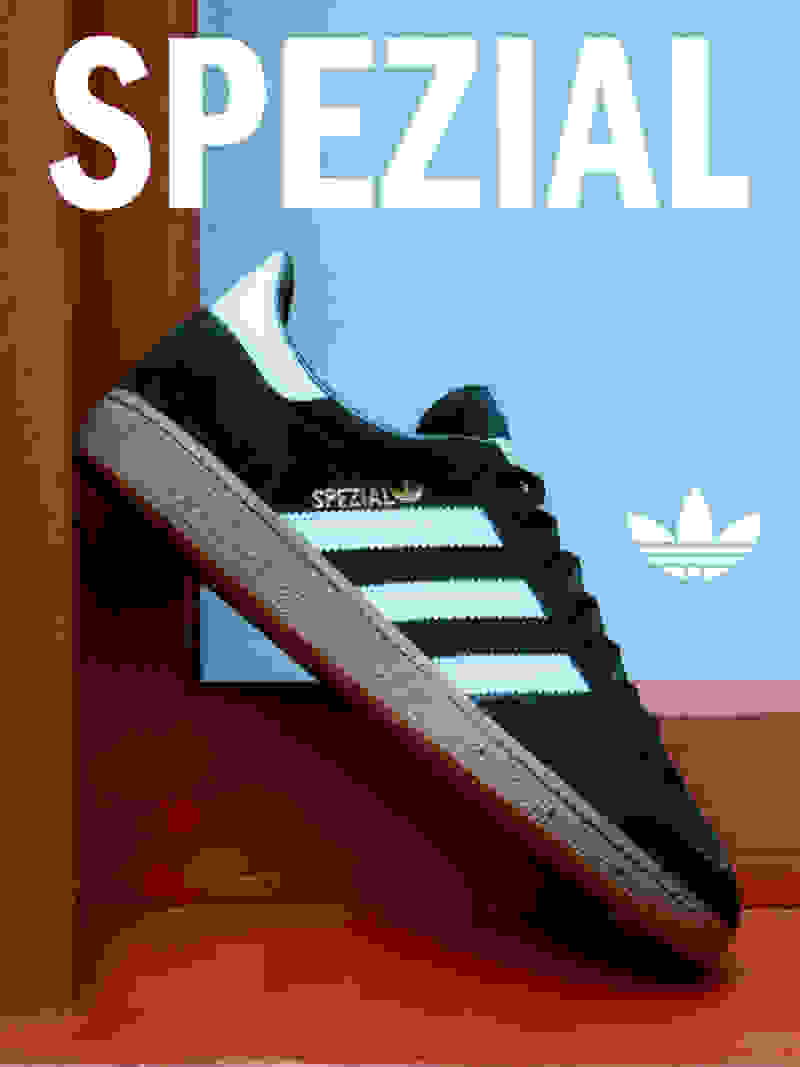 A pair of black and white Adidas Spezial sneakers is displayed on a red and blue background.