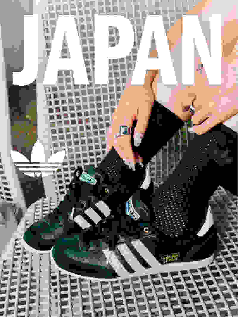 The image shows a pair of black and white Adidas sneakers with the word "JAPAN" prominently displayed in the background.