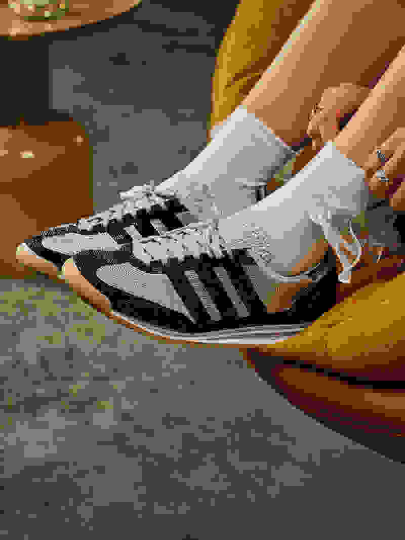 A pair of white and black sneakers with laces sits on an orange chair, with a blurred background suggesting a cozy, indoor setting.