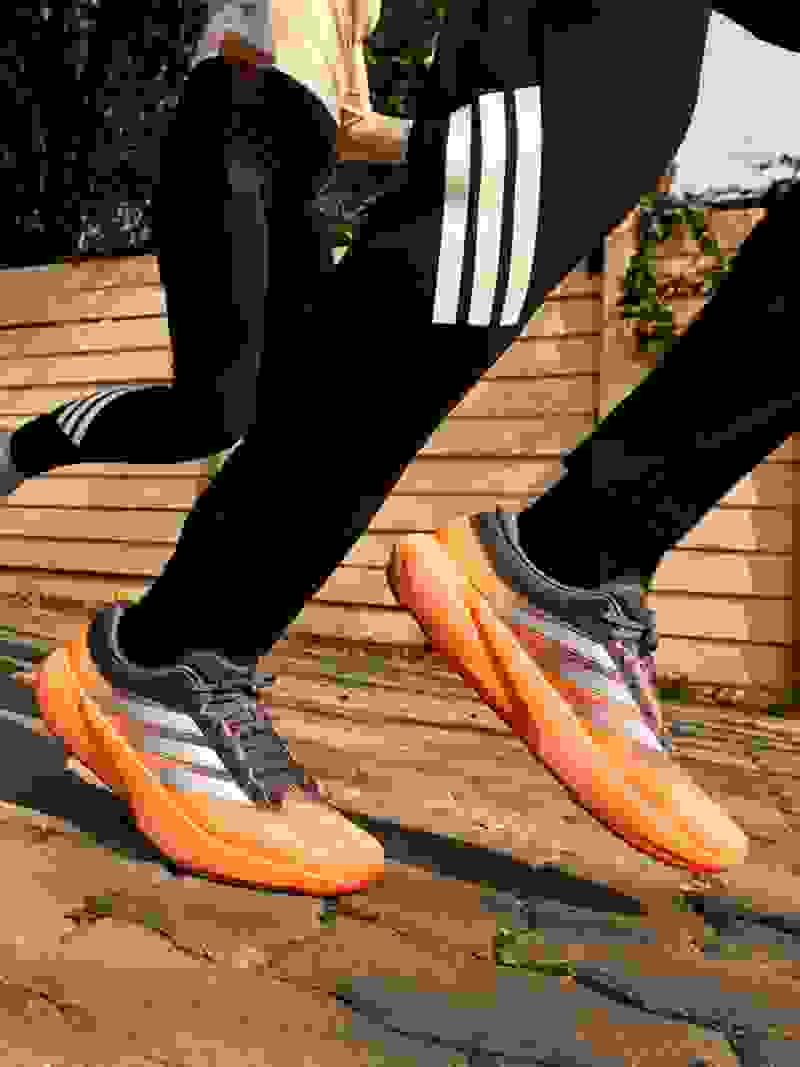 A young person wearing a black jacket stands against a plain beige background, their gaze directed slightly off-camera.