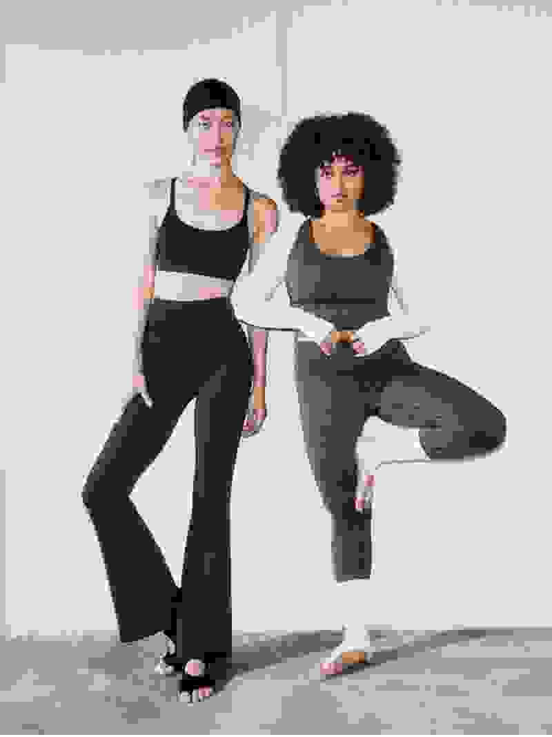 Two women wearing athletic clothing are posing against a plain white background.