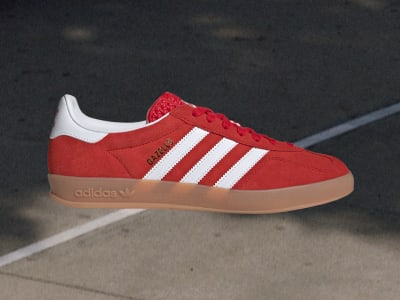 Red Adidas Gazelle shoe with white stripes and brown sole, featuring a suede toe cap and a gold SAMBA label.
