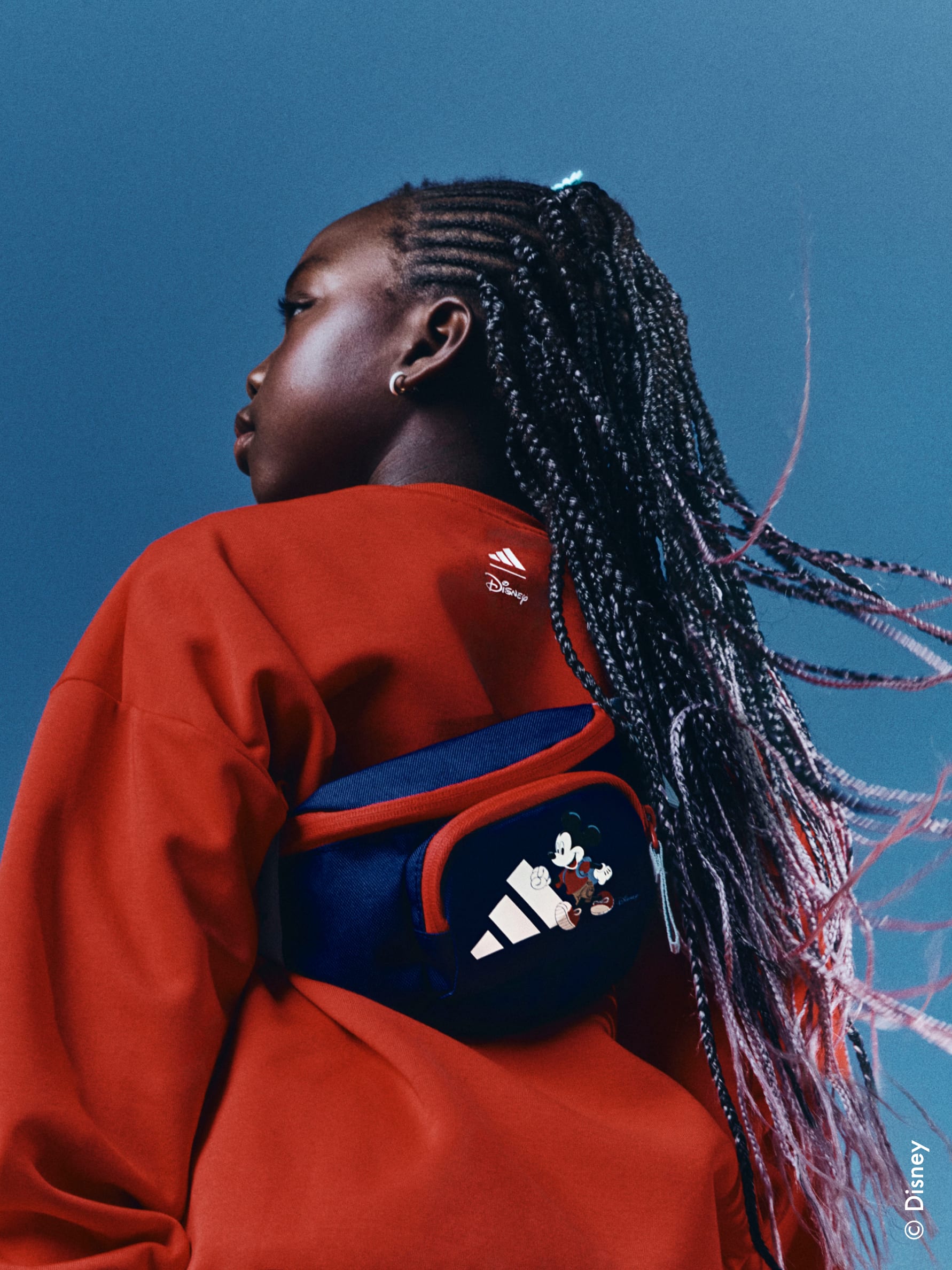 Close up of child outside with a blue backdrop, wearing the adidas | Mickey & Friends collection