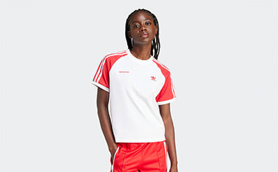 A young person wearing a white and red sports jersey stands against a plain white background.