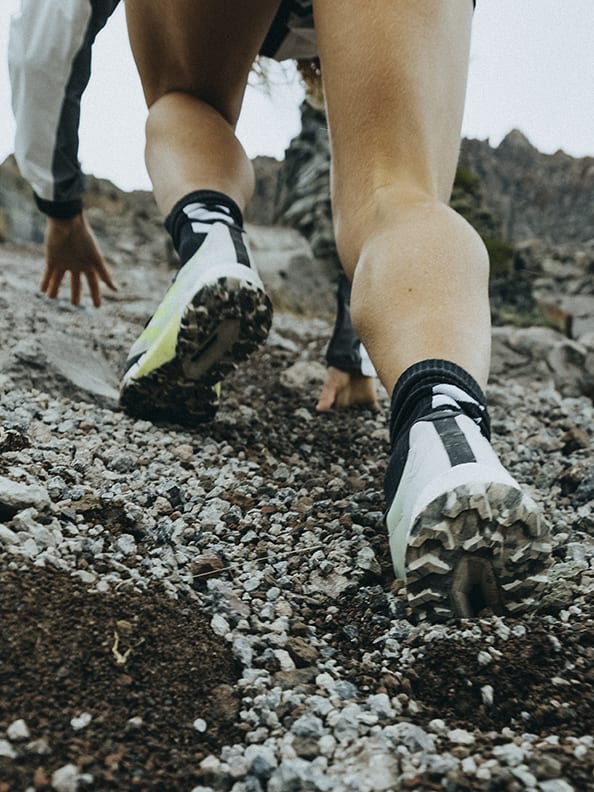 Athlete Ekaterina wearing the Agravic Ultra running up rocky mountain trails