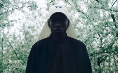 A man with black hair and a black Y-3 shirt stares down at the camera.