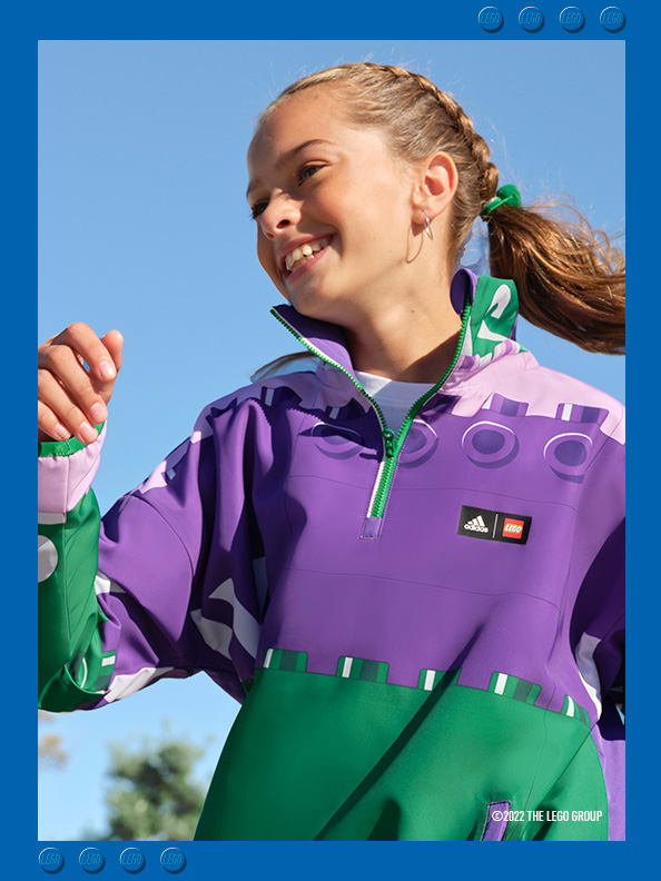 Girl smiling and playing wearing a purple adidas LEGO tracksuit top