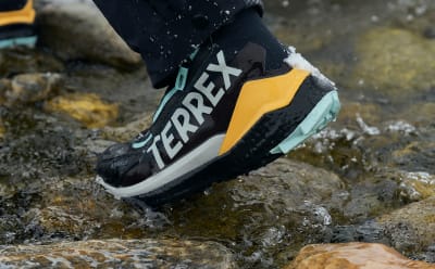 Feet wearing the Freehiker COLD.RDY shoes whilst walking on a rocky ground