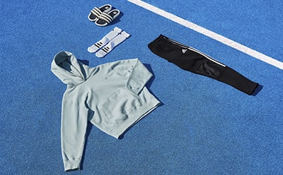 Hoodie, loungewear pants, socks and slides displayed together on sports gym floor.