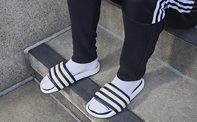 Close up of man wearing pairs of socks and slides.