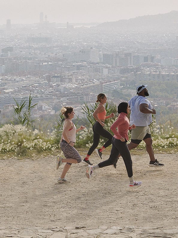 Group of people running on a hill wearing adidas.