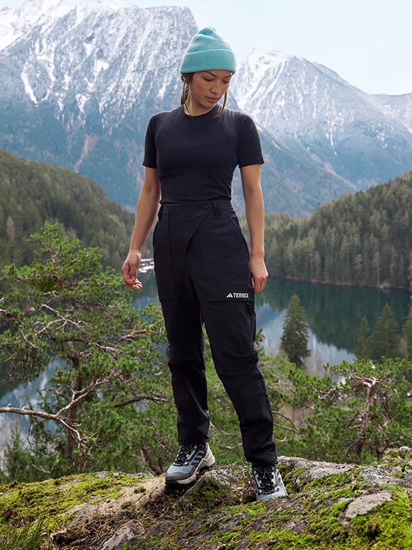 A person standing on a rock in front of a lake