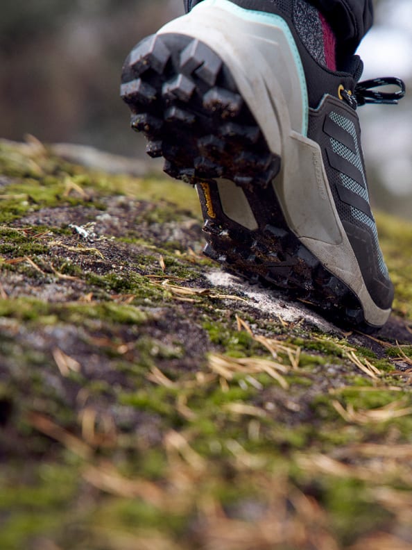 A montage of images of men and women wearing the Terrex Adventure Wardrobe collection against an outdoor lake and forest backdrop, including cropped view of feet in Terrex Swift R3 GTX shoes.