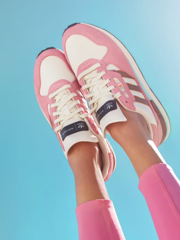 Pink adidas women's sneakers from the adidas x Rich Mnisi Pride Collection are photographed against an endless blue sky.