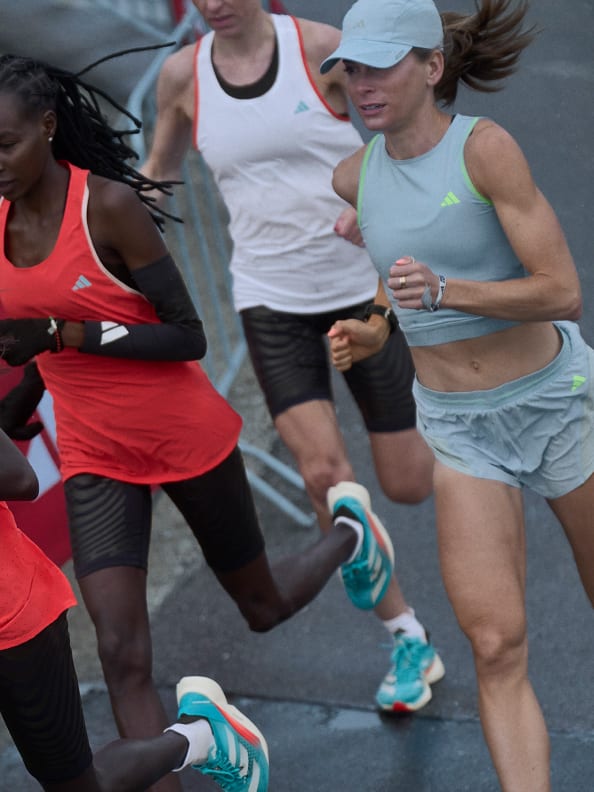 Four female athletes wearing Adizero performance apparel while running outside