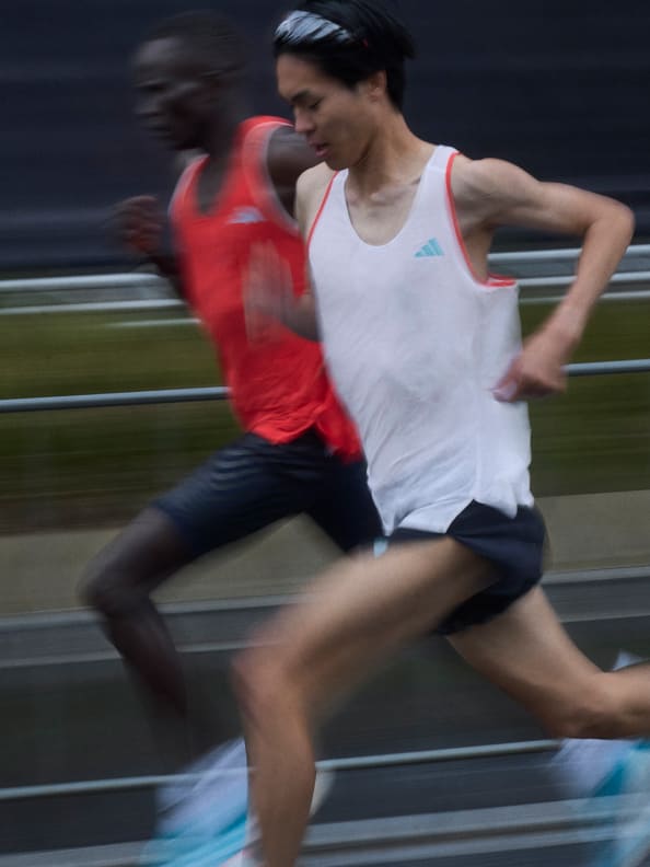 Two male athletes wearing Adizero performance apparel while running outside