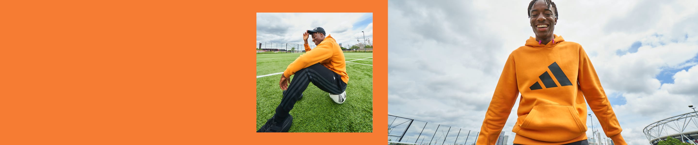 English footballer Noni Madueke looks up at the camera, smiling, as he stands on a football pitch in an orange adidas hoody.