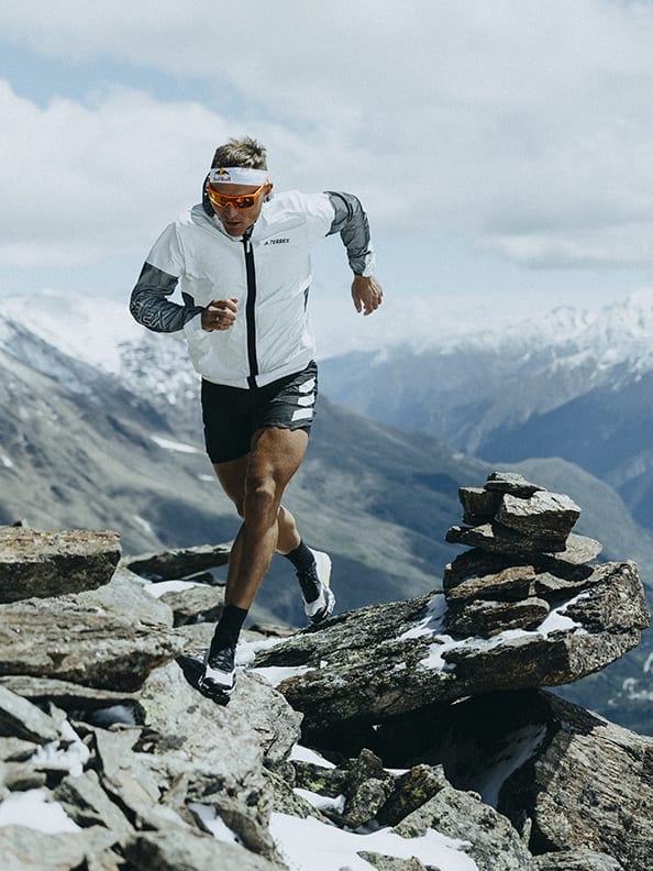 Athlete Dima wearing the Agravic Ultra running up rocky mountain trails