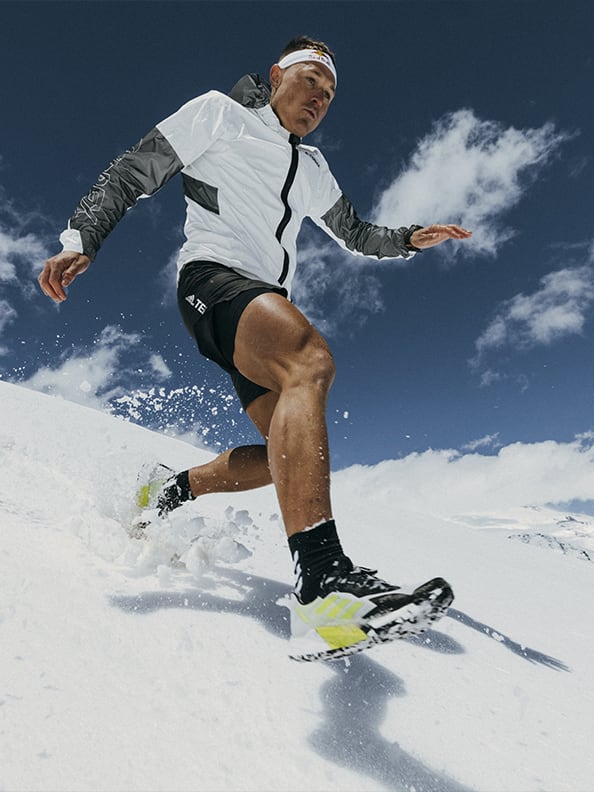 Athlete Dima wearing the Agravic Ultra running down snowy mountain trails