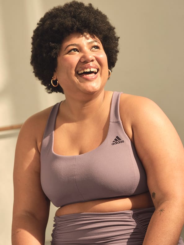 Image of a plus sized model laughing, wearing a lavendar sports bra.