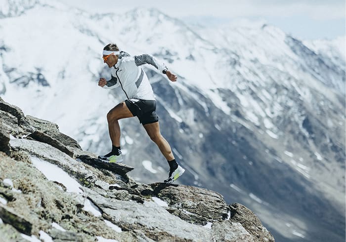 Athlete Dima wearing the Agravic Ultra running up rocky mountain trails
