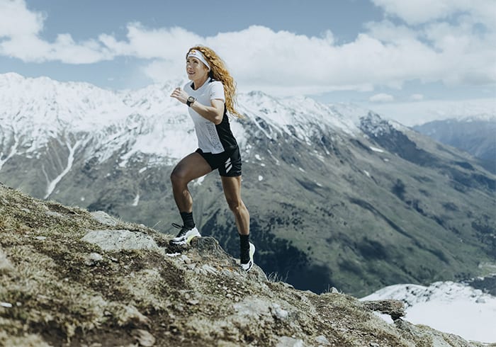 Athlete Ekaterina wearing the Agravic Ultra running up rocky mountain trails