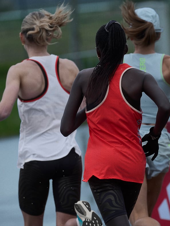 Rear view of three athletes wearing Adizero performance apparel while running outside