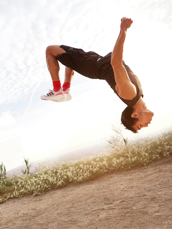 Image of man doing a backflip outdoors and wearing Ultraboost Light shoes.