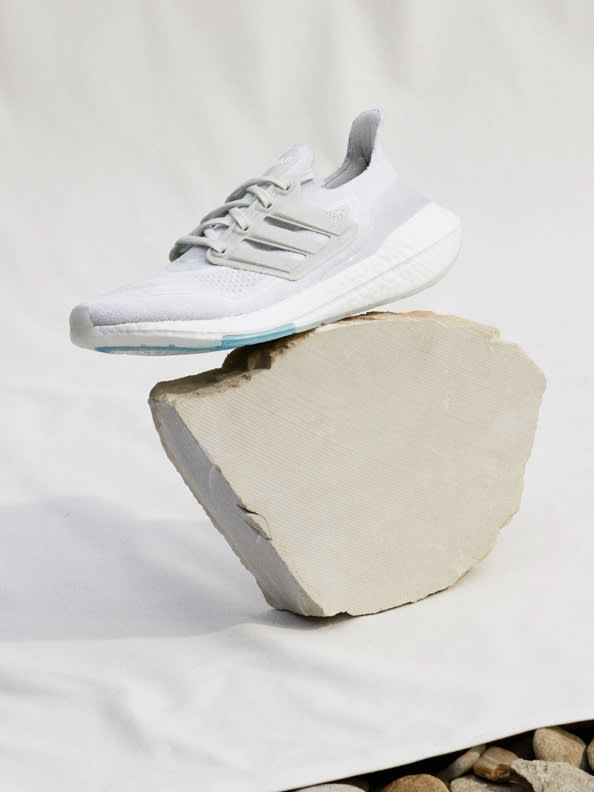 Pair of Ultraboosts with light background, one shoe on its side to show sole.