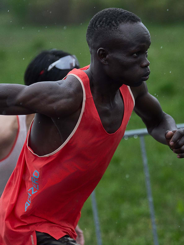 Male athlete wearing red Adizero performance running vest while running outside