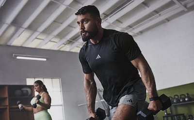 Female and male in the gym, lifting weights while wearing the adidas strength training collection