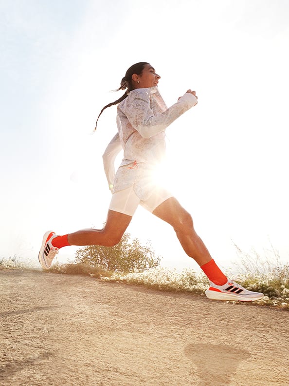 Image of woman running outdoors wearing Ultraboost Light shoes and adidas running gear.