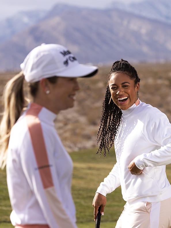 Two women laugh on the golf course.