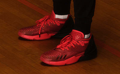 A close-up view of red high-top basketball shoes on a hardwood court.
