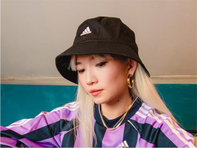 Close crop of girl wearing adidas sportswear jersey and bucket hat.
