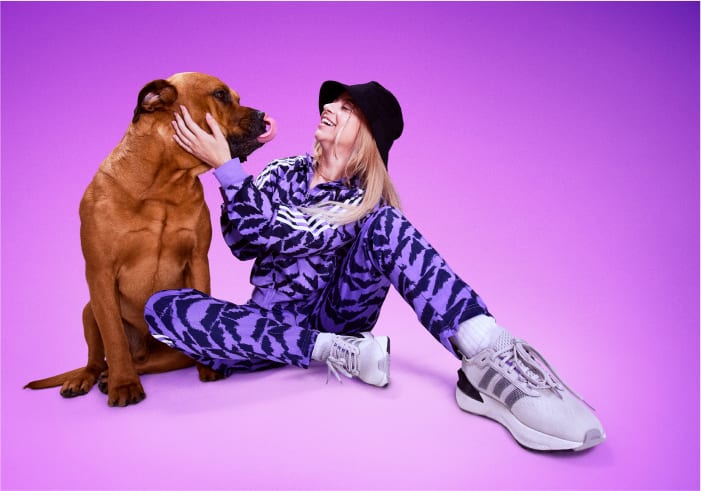 Pro gamer Carolina Voltan seated on the ground with dog, dressed in purple adidas tracksuit and bucket hat