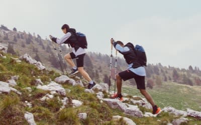 Woman and man wearing TERREX speed hiking collection apparel and shoes hiking in nature.