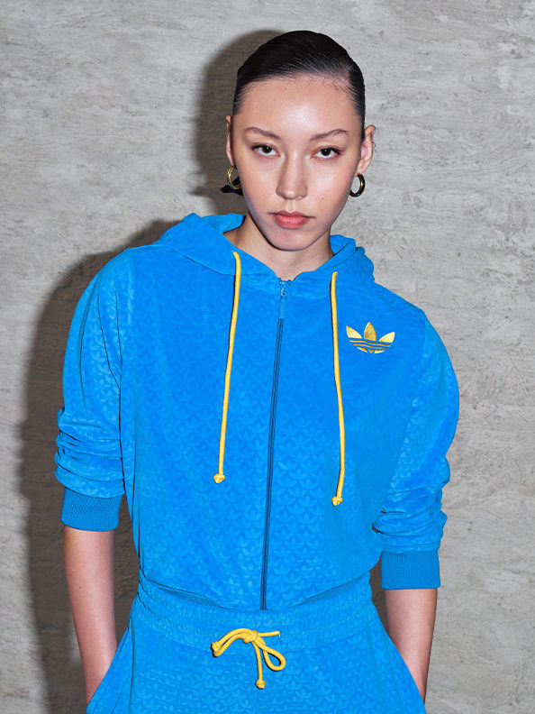 A model wearing a blue and yellow velour tracksuit from the latest adicolor collection