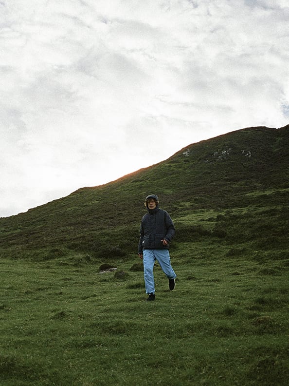 male model wearing the mtbr anorak walking hikinh in highland scenery