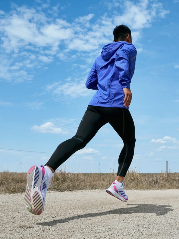 Man runs along a dirt road in the sunshine in Adizero SL wearing Adidas running apparel